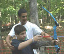 A 4-H leader helping a 4-H'er with a bow and arrow.