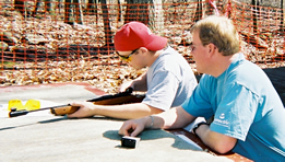 A 4-H leader helping a 4-H'er check a rifle.