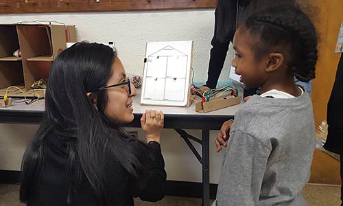 A STEMP Ambassador talkign to a smaller child.