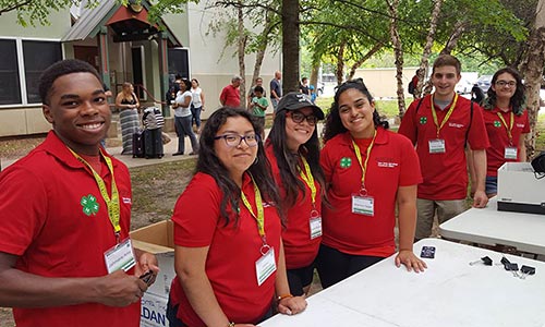 A group of STEM Ambassadors standing outside in front of tables.
