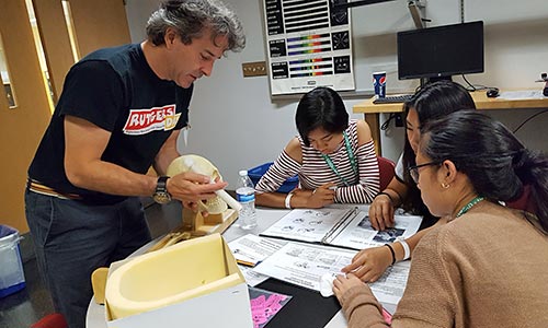 A sciencist explaining something to three teens.