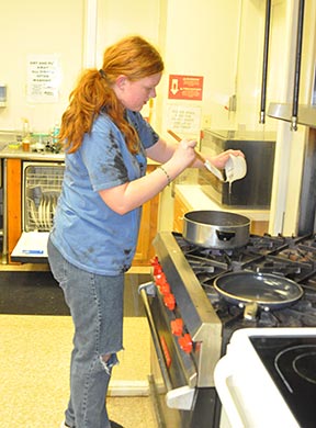A 4-H'er using a stoce to cook.