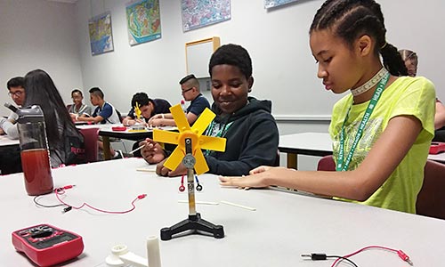 Two children at a table working on electronics.