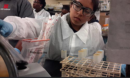 A child in a lab coat working in a lab.